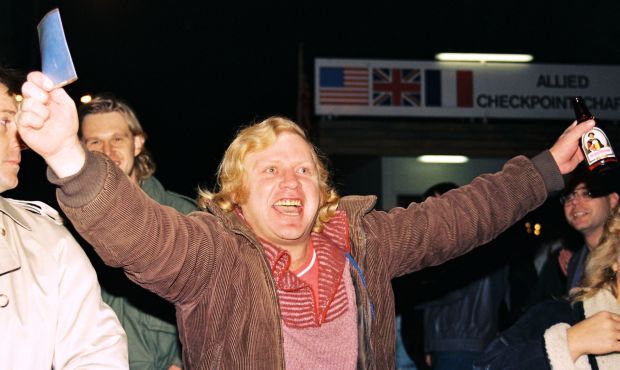Jubilation at Checkpoint Charlie GDR documents in one hand a West German beer in the other